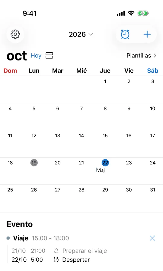Calendario de CAlarm con octubre de 2026: el evento Viaje el día 22 y, debajo, su aviso «Preparar el viaje» la noche anterior y la alarma de las 5:00